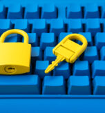 Yellow padlock and key on a bright blue keyboard, representing Cyber Essentials certification