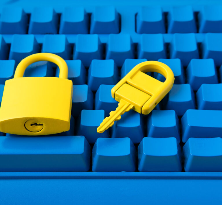 Yellow padlock and key on a bright blue keyboard, representing Cyber Essentials certification