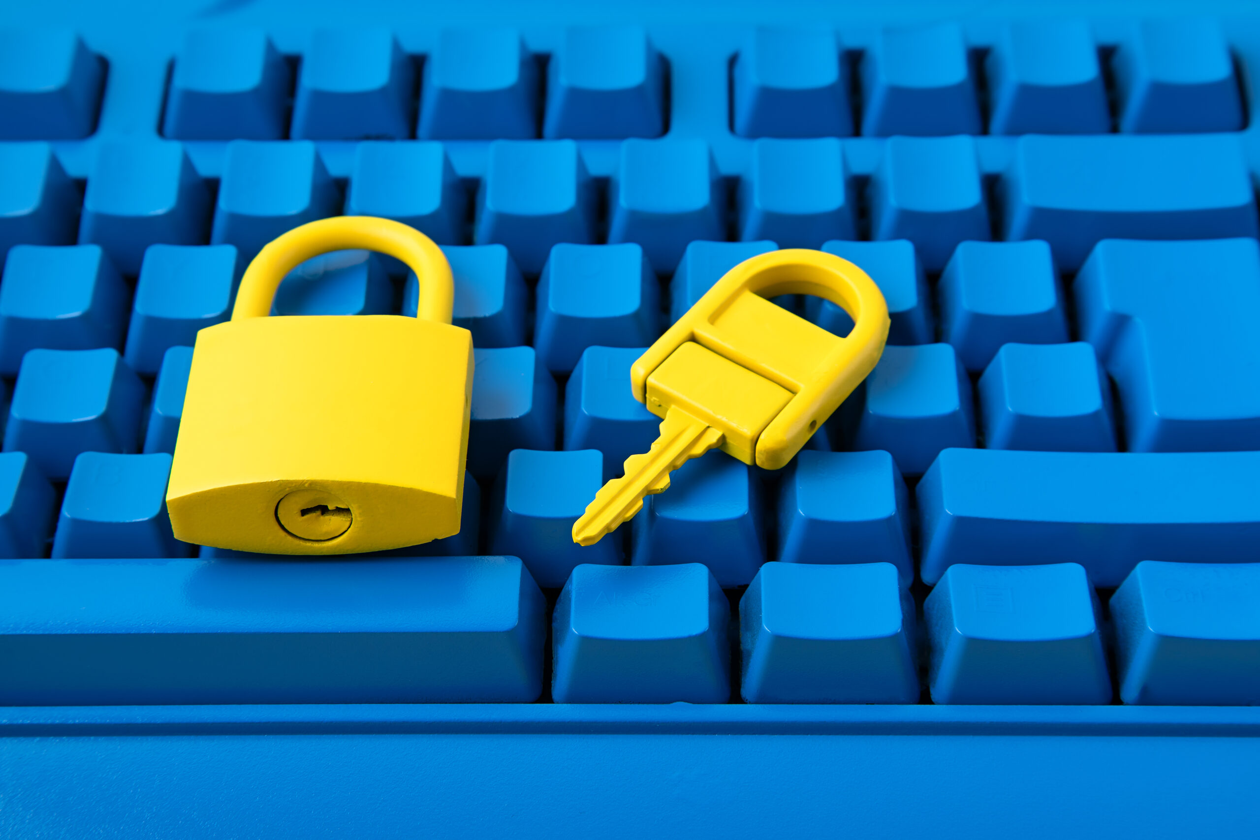 Yellow padlock and key on a bright blue keyboard, representing Cyber Essentials certification