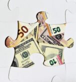Missing puzzle piece showing different currency notes underneath, symbolising that the right IT support for financial services may be the missing piece for your success