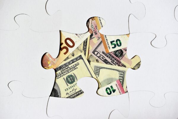 Missing puzzle piece showing different currency notes underneath, symbolising that the right IT support for financial services may be the missing piece for your success