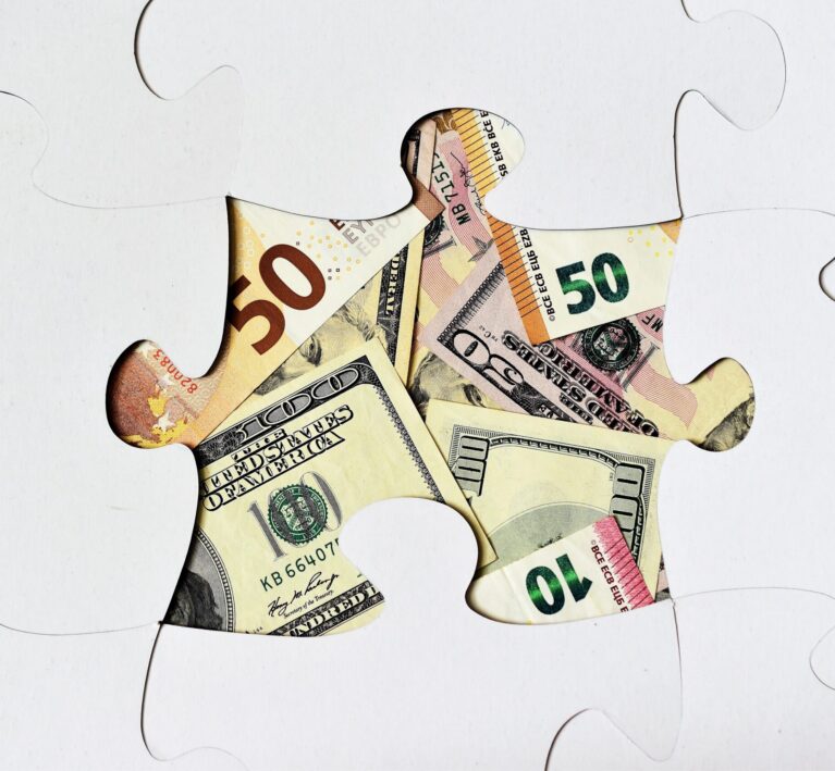 Missing puzzle piece showing different currency notes underneath, symbolising that the right IT support for financial services may be the missing piece for your success